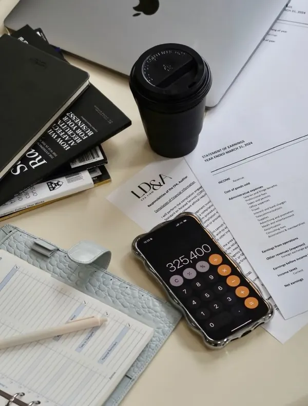 Mesa com calculadora no celular, planner, café e documentos