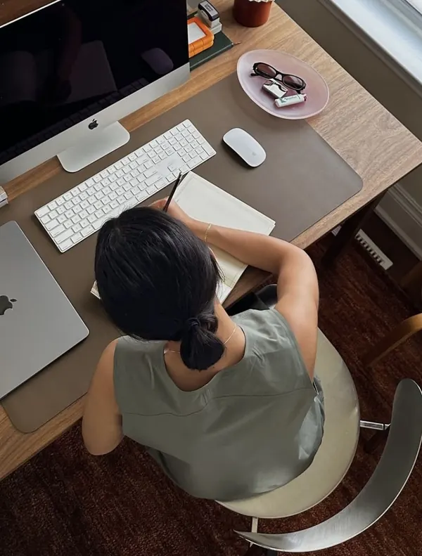 Mulher trabalhando em sua mesa de escritório, com computador e planner, vista de cima